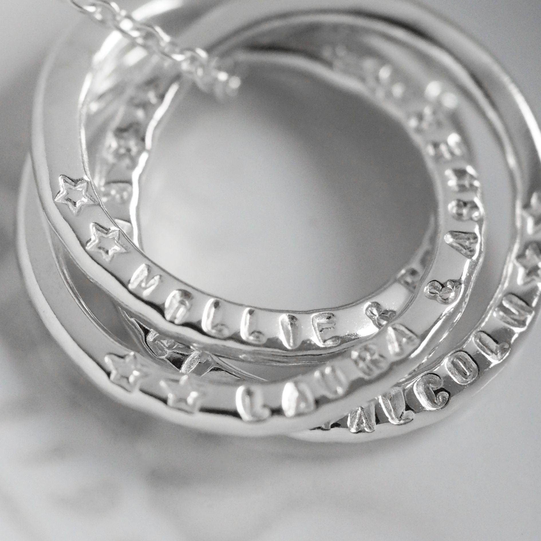 Close up of stamping on a family interlocking ring necklace showing the outline star stamps