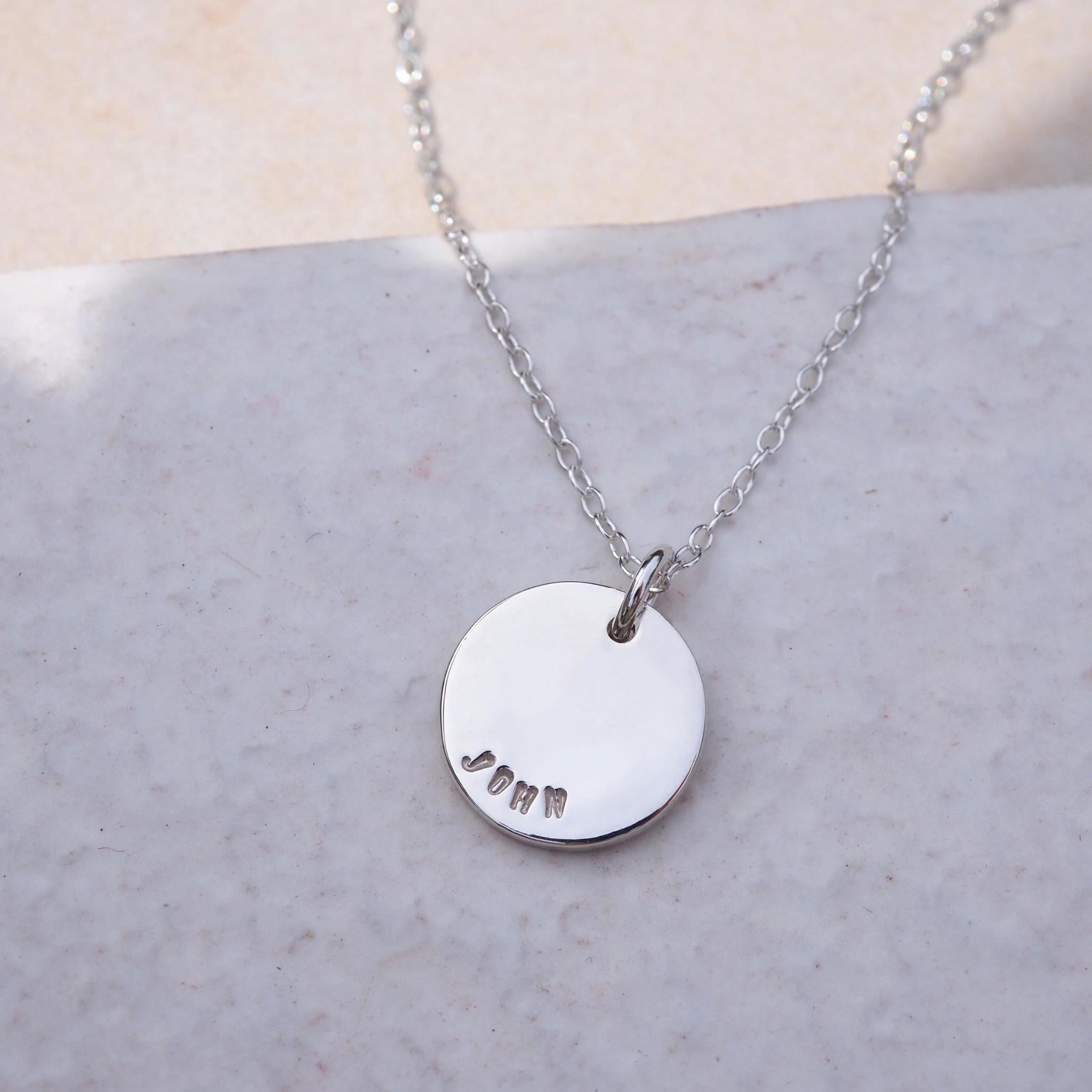 Double-sided disc necklace in silver, hand-stamped with names on both sides