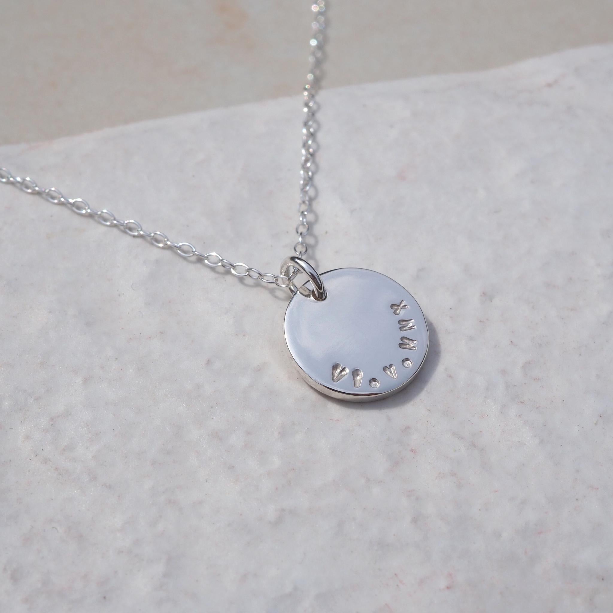 Hand-stamped double-sided disc necklace in sterling silver on a trace chain