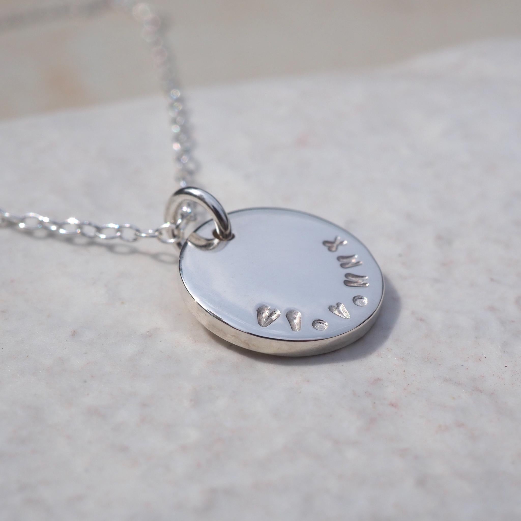 A double-sided disc necklace in sterling silver, hand-stamped with a special date in roman numerals