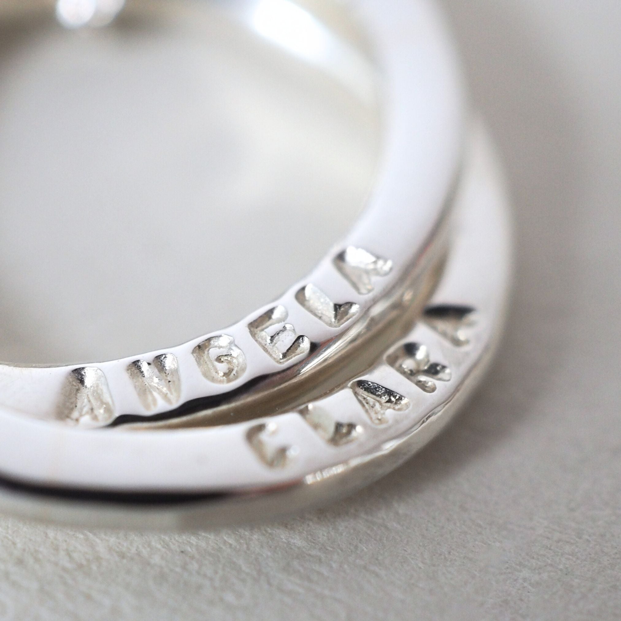Close up of hand-stamped names on a personalised sterling silver necklace