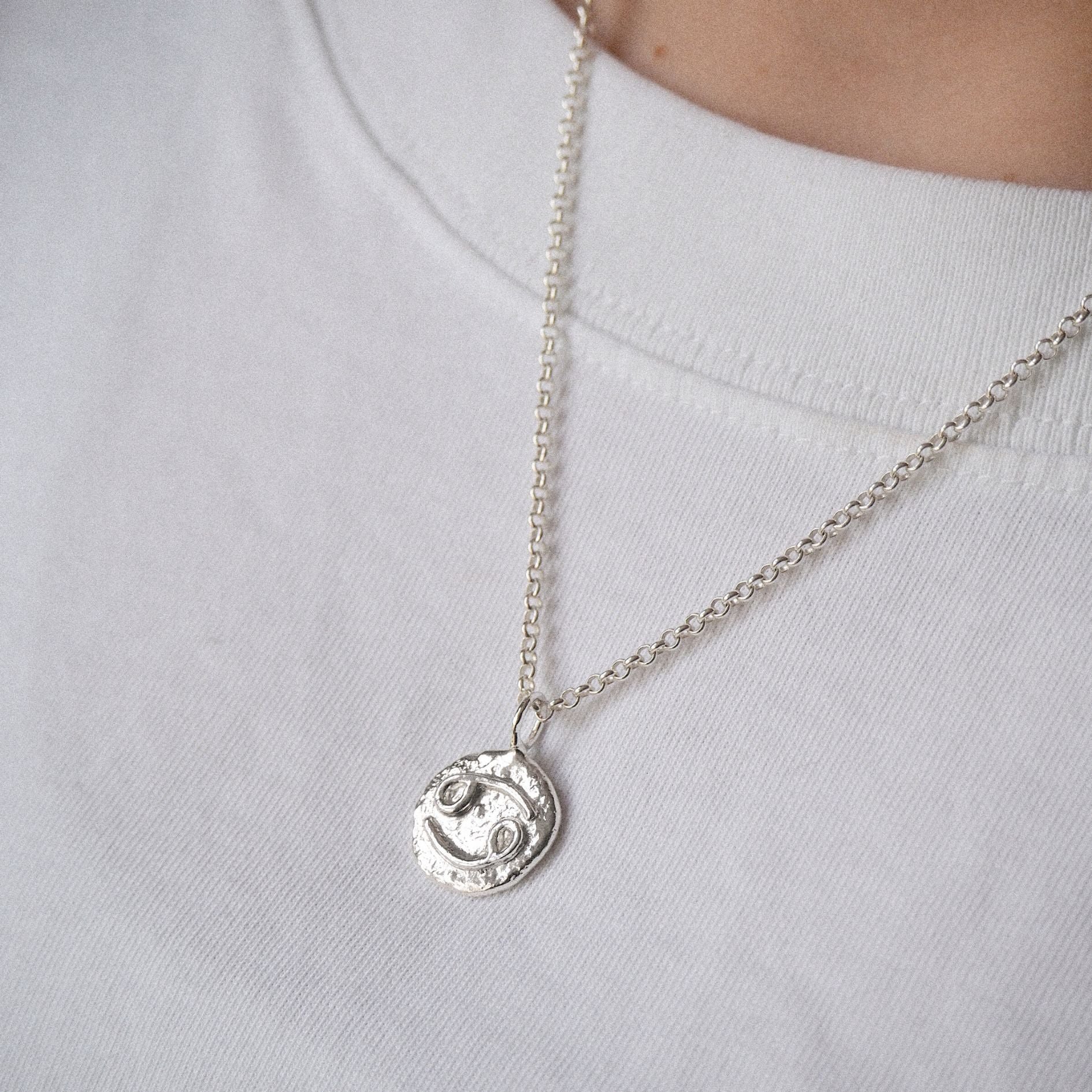 Model wearing a molten cancer zodiac necklace n sterling silver