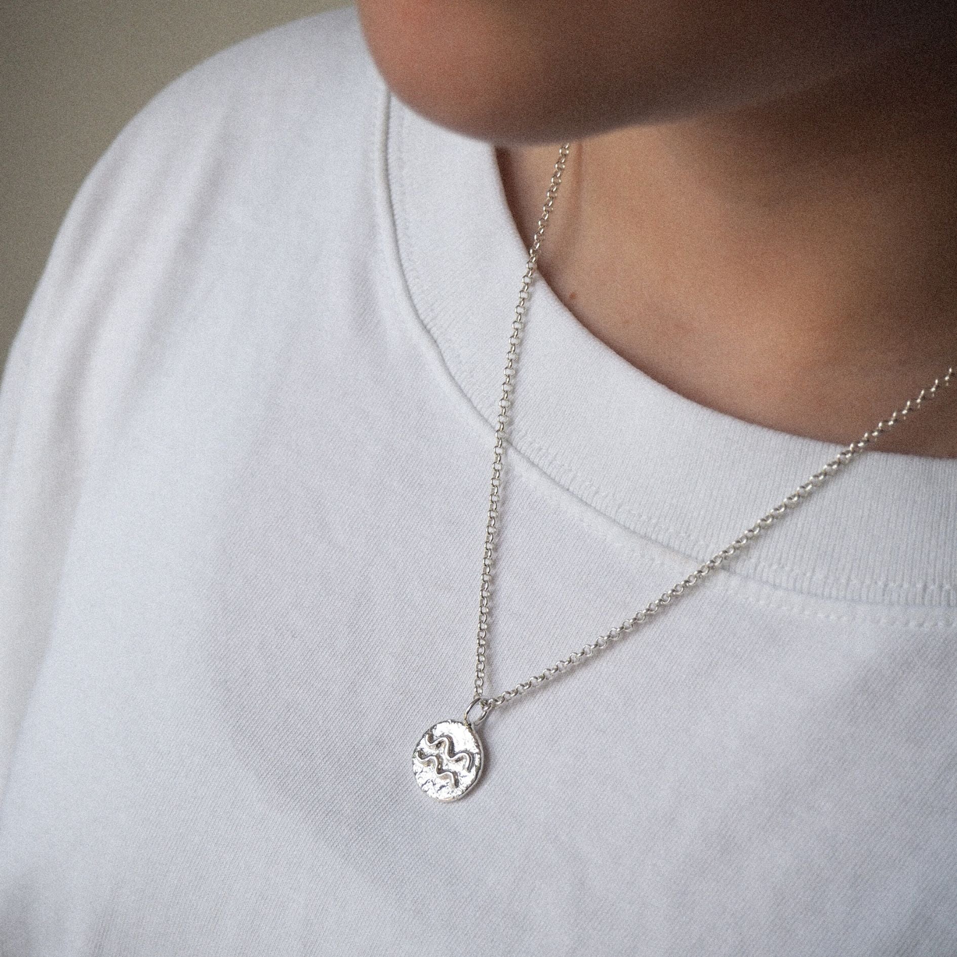 Model wearing a handmade molten zodiac necklace in sterling silver