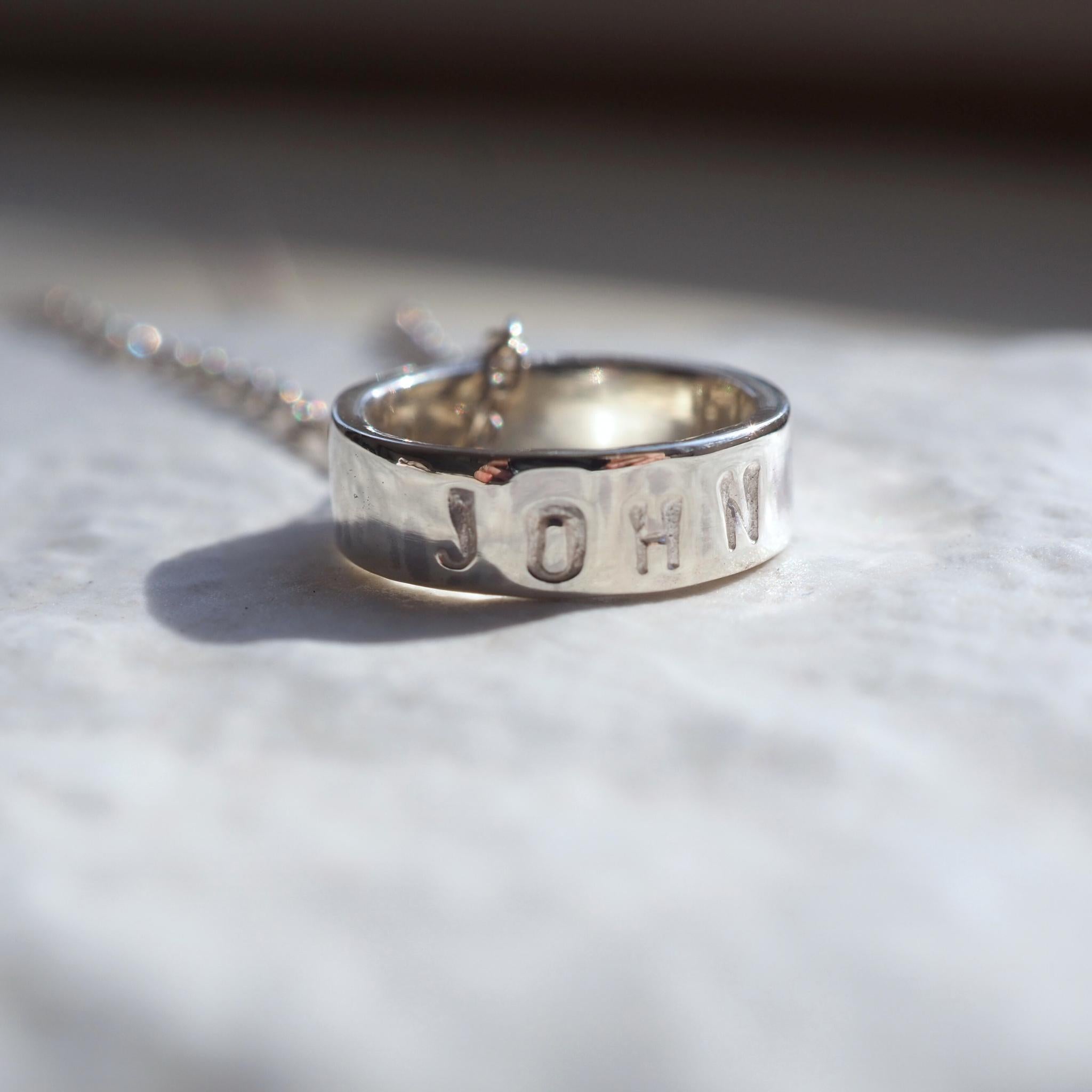 Personalised sterling silver scroll necklace, custom-stamped with a name 